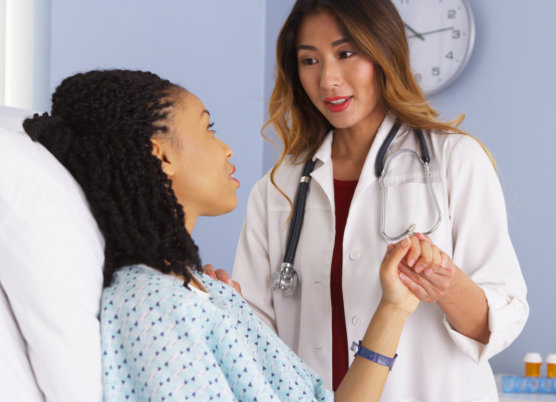 Doctor holding hand of black woman patient in hospital